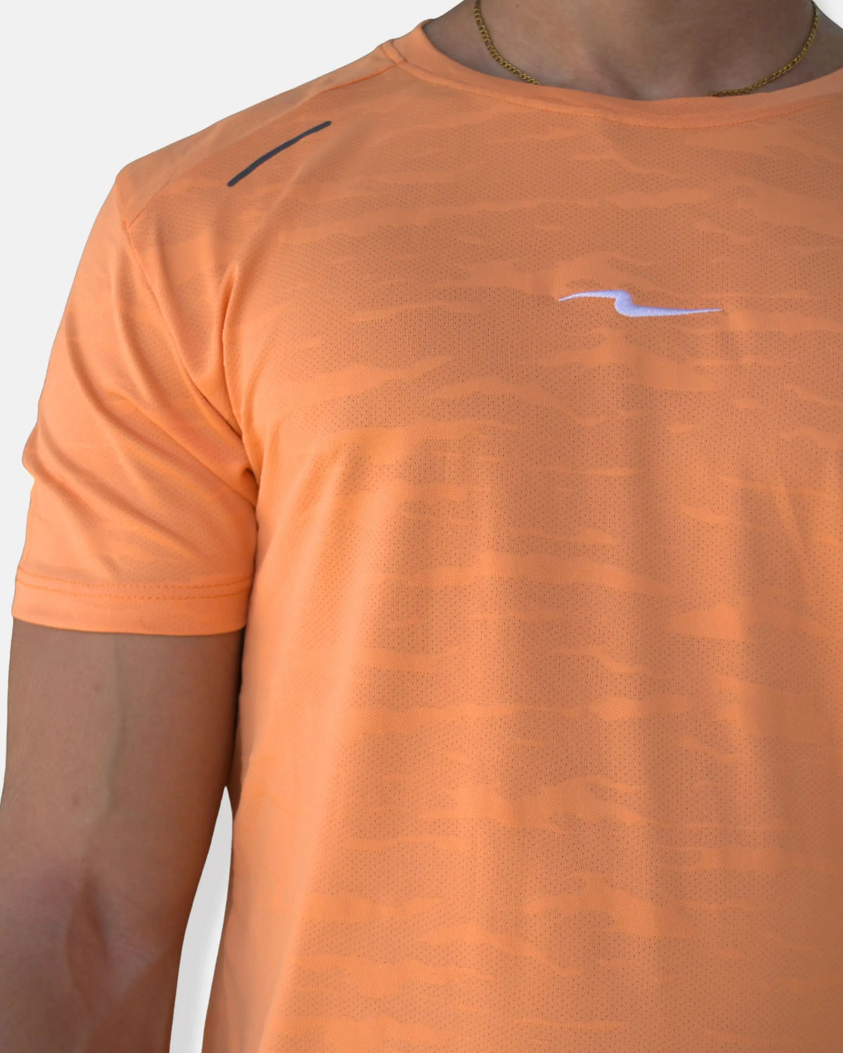 Zoom sur le tissu micro-perforé à motif camouflage du t-shirt de sport orange