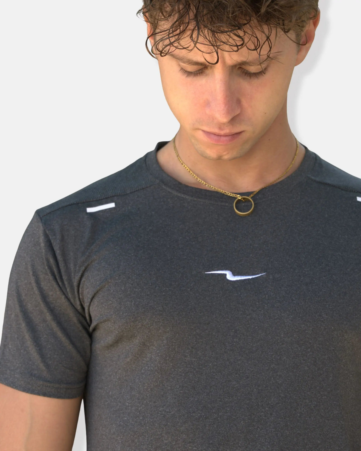Zoom sur le logo éclair brodé blanc du t-shirt de sport gris